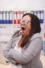 Obraz premium female secretary with glasses and blazer yawns terribly with her mouth open