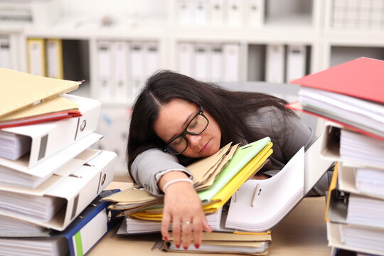 female secretary with glasses sits at the desk and fell asleep from all the work