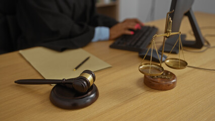 Woman typing at an office desk with a gavel and scales of justice, exemplifying a legal workplace setting.