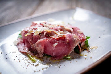 Beef Carpaccio on Arugula, Seasoned and Topped with Parmesan and Drizzled with Olive Oil