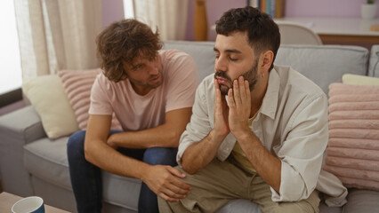 Man comforting another man in a living room with a couch, showing empathy, support, and friendship in a home environment.