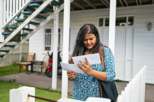 Woman collecting mail in front of her house