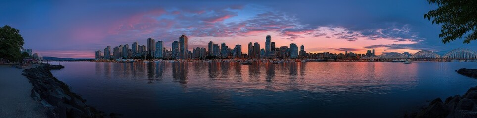 Fototapeta premium City Skyline at Dusk: A breathtaking panoramic view of a modern cityscape bathed in the soft glow of twilight, with the city skyline reflected in the calm water.