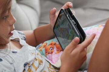 Criança de frente com celular jogando e com olhar diretamente para tela.