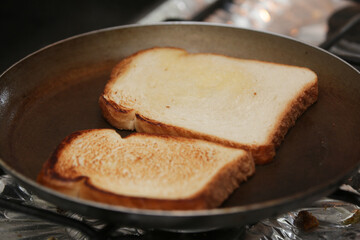 Duas fatias de pão de forma sobre a frigideira fritando para café da manhã.