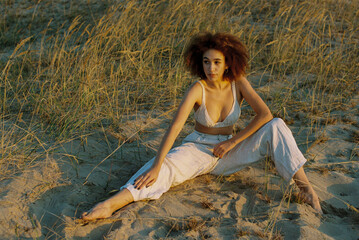A young woman with afro hair posing in the sand dunes