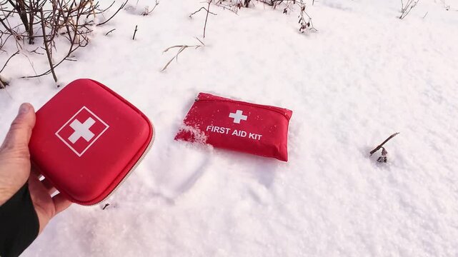 Two first aid kits are placed on a blanket of fresh white snow, emphasizing the crucial importance of safety and preparedness for all winter outdoor adventures one might undertake