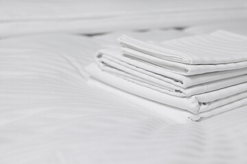 Stack of clean linens on bed indoors, closeup. Space for text
