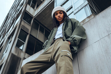 Fashion shoot of a female model wearing modern streetwear in an urban setting.