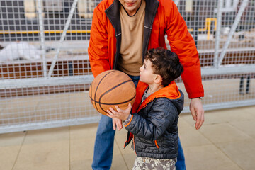 Father and little son bonding over basketball court outdoor practice.