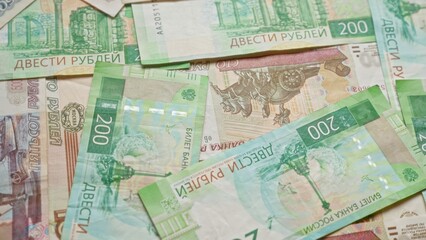 Russian ruble banknotes scattered on a surface, showing various denominations and close-up details of currency design elements.