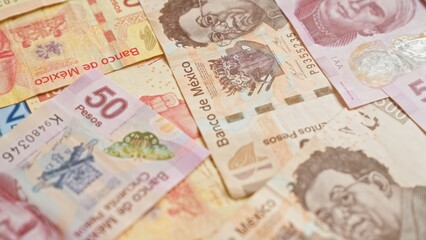 Mexican banknotes of various denominations scattered on a surface, showcasing colorful mexican pesos currency with intricate designs and historical figures.