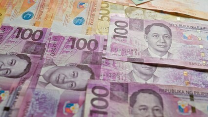 Philippine banknotes scattered, showcasing various denominations of pesos