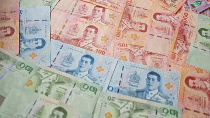 Obraz premium Thai banknotes in various denominations including 20, 50, 100, and 1000 baht from thailand are arranged in a scattered manner highlighting the vibrant, detailed designs.