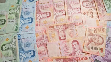 Fototapeta premium Colorful thai baht banknotes spread out in a close-up view, showcasing various denominations and intricate designs, representing the currency of thailand.