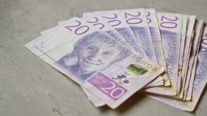 Swedish banknotes spread on a concrete surface, highlighting the detail and design of the twenty kronor currency.