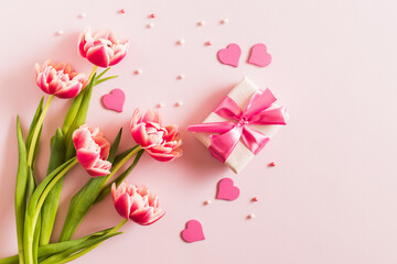 Obraz premium Pink tulips and hearts, gift box with ribbon on light pink background