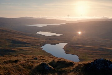 Fototapeta premium Wind turbines spin gracefully in a vast field under clear blue skies, promoting clean energy in a serene landscape with mountains and reflective waters