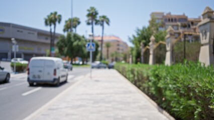 Blurred street with white van, palm trees, buildings, and cars in the sunny outdoor urban area with defocused background