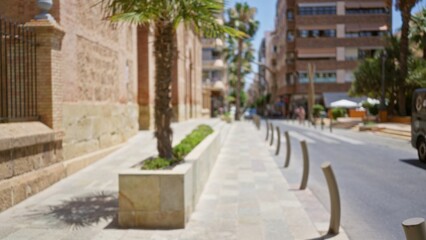 Defocused urban street view with trees and buildings on a bright sunny day, capturing greenery and architecture in a cityscape setting.