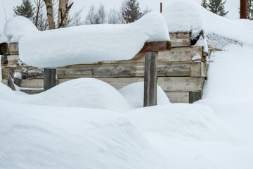 A massive pile of snow in front of a building, almost covering the windows. The scene highlights extreme winter conditions