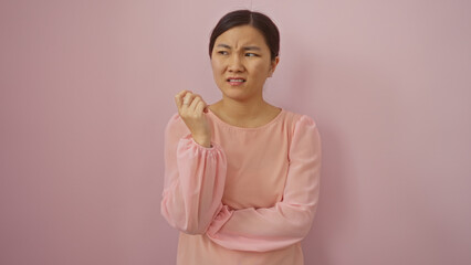 Obraz premium Woman looking skeptical wearing pink blouse against a pink background symbolizes doubt and contemplation with an intriguing expression and thoughtful pose.