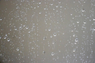 Close-up of raindrops on a glass surface, creating a beautiful pattern and texture, perfect for backgrounds or nature-themed projects.