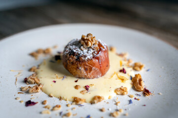 Baked Apples Stuffed with Walnuts and Vanilla Cream Sauce on a Rustic Wooden Background