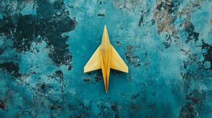 A handmade paper plane lies on a blue background, viewed from the top