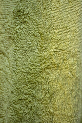Close-up of a textured green towel showcasing soft fibers and intricate patterns. Ideal for home decor themes and presentations.