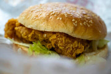 Delicious crispy fried chicken sandwich with lettuce in a sesame seed bun, served in a casual dining setting, perfect for fast food lovers.