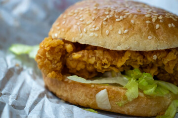 Close-up view of a crispy fried chicken sandwich with lettuce in a sesame seed bun. Perfect for food photography and culinary use.