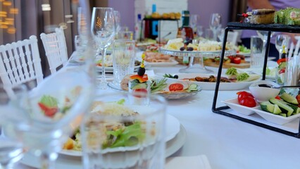 Professional catering team arranging sophisticated appetizers, canapes on pristine white plates, positioning crystal glassware for upscale event's refined dining experience
