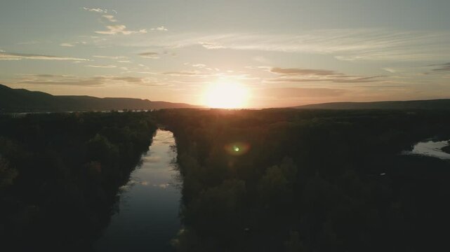 Tranquil river reflecting golden sunset over lush green landscape