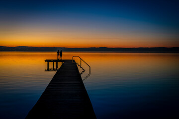 Liebespaar auf einem Holzsteg am Starnberger See im Abendrot