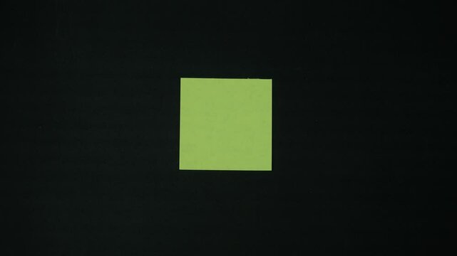 A girl's hand attaches a blank paper note to the wall as a reminder, several more colorful ones appear nearby. Stop motion