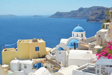 Obraz premium Oia village on Santorini island, Greece. Traditional and famous houses and churches with blue domes over the Caldera, Cyclades islands Aegean sea.