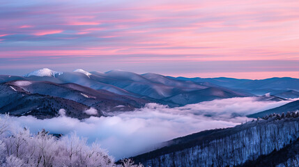 Naklejka premium A photograph of the view from an alpine mountain top at night. Snow-covered mountains with fog below and a pink sunset sky. Beautiful winter landscape, romantic sunset or sunrise with snowy mountains.