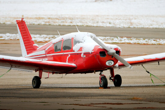 Small Red Airplane Single Engine Private Plane on Runway Covered in Snow in the Winter Wintery Snowy