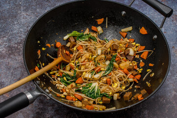 Vegan stir fry in cast iron wok consisting of mixed vegetables,  mung bean sprouts, seitan