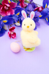 Easter scene with chiken in funny rabbit's ears, flowers in background.