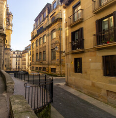 Narrow alley with traditional buildings, balconies, and street lamps in the old town of San Sebastian, Spain. Urban architecture.