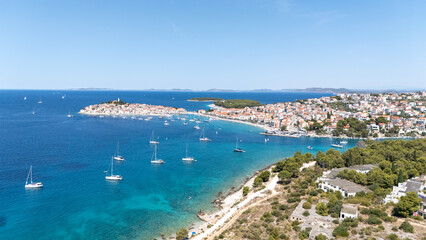 Primosten Town, Adriatic Sea, Croatia. Idyllic Beach on Mediterranean Sea Coast Near Medieval Primosten City in Croatia. Summer Holidays Travel Destination. Blue Sky, Azure Water.