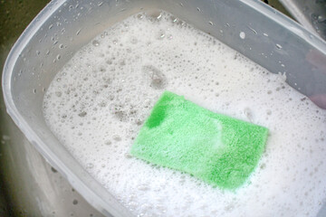 Dirty dishes in kitchen sink. Sponge in water with bubbles dishwashing liquid.