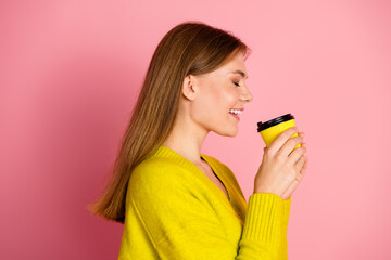 Smiling Woman Holding Yellow Coffee Cup on Pink Background Depicting Leisure and Joy