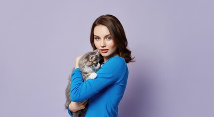 Fototapeta premium Young caucasian female holding fluffy cat against pastel lavender background