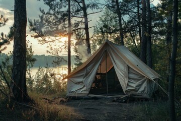 Smoke rising from campfire near canvas tent pitched in tranquil forest by lake at sunset