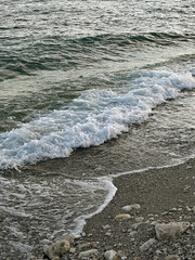 Gentle spring waves caress a rocky Istanbul shoreline under daylight, capturing nature's serenity and timeless beauty in a peaceful moment