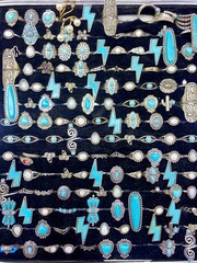 Experience the allure of opulence up close with a detailed view of gold necklaces, rings, and chains elegantly showcased in a beauty retail store window.