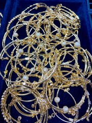 Experience the allure of opulence up close with a detailed view of gold necklaces, rings, and chains elegantly showcased in a beauty retail store window.